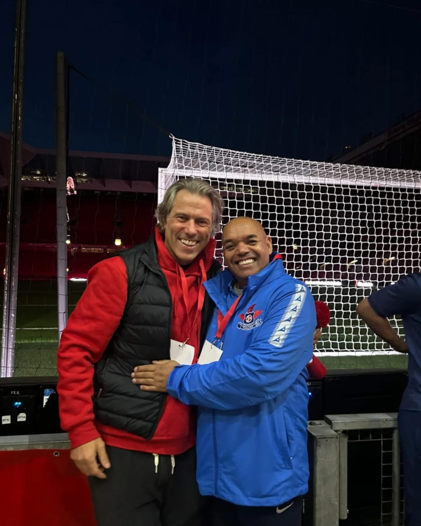 John Bishop with Liverpool Homeless Football Club chief executive at a floodlit pitch